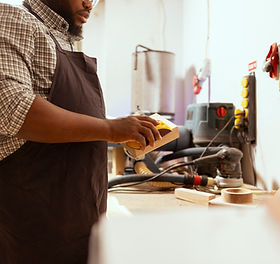 2400-african-american-man-in-assembly-shop-using-sandpaper-for-sanding-wooden-surface-befo