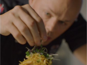 person garnishing a dish