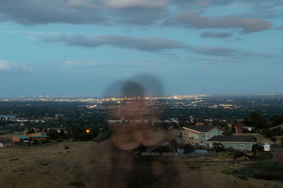 long exposure shot of a man moving in front of a city skyline, foregrounded by houses in a field