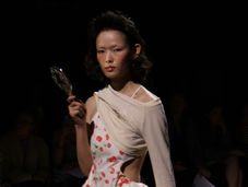 A model from Yuhan Wang's SS27 collection holding a mirror and fixing the camera