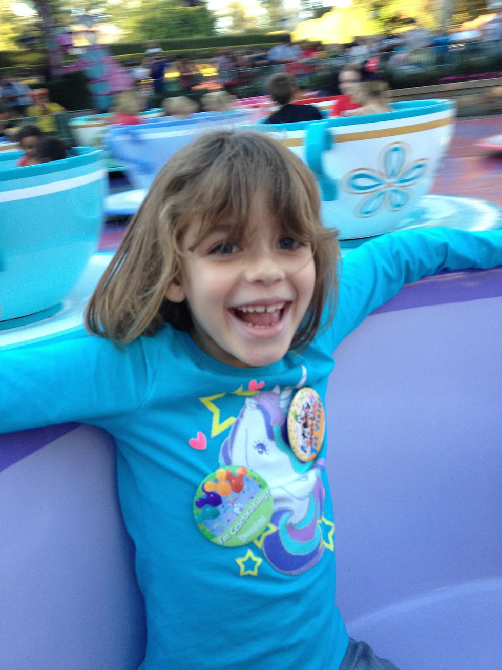 A young girl riding the teacups with her dad at Disney