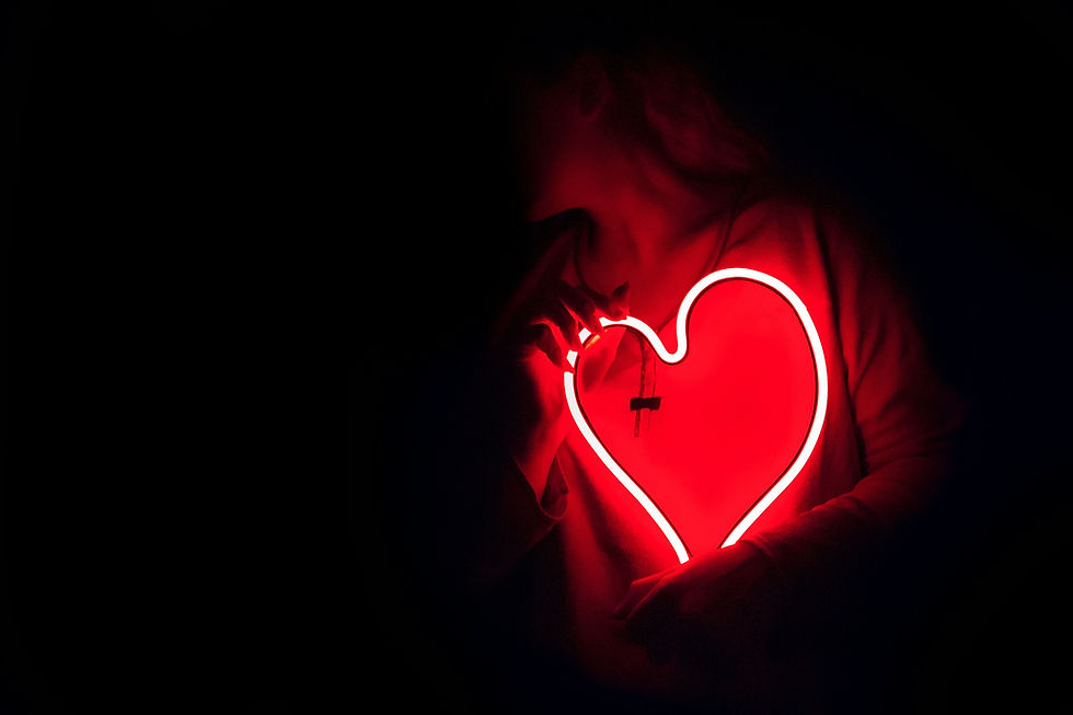 red neon outline of a heart held by someone