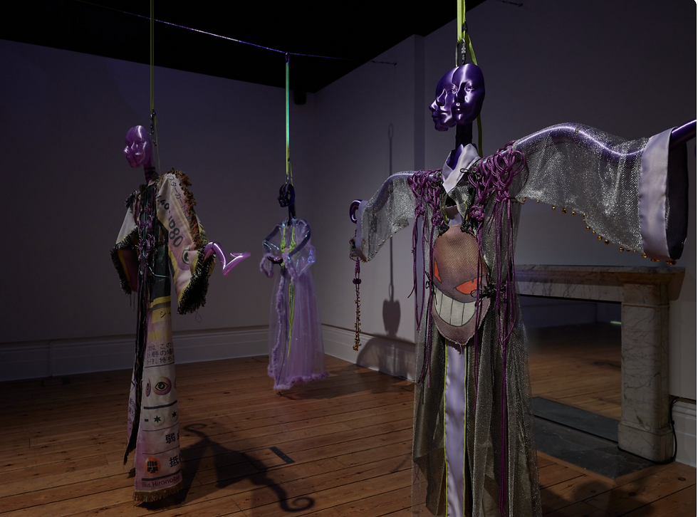 Three statues suspended from the ceiling, each with three purple faces. Wearing soft fabric night dresses.