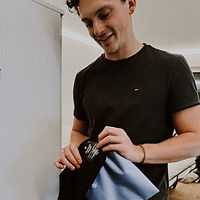 Ein aufmerksamer junger Mann zeigt die Allthingsdaysie-Unterwäsche, ein Geschenk für seine Freundin, als Zeichen seiner Sorge um ihre Gesundheit und Wohlbefinden, verkörpert durch die durchdachte Wahl der Produkte.