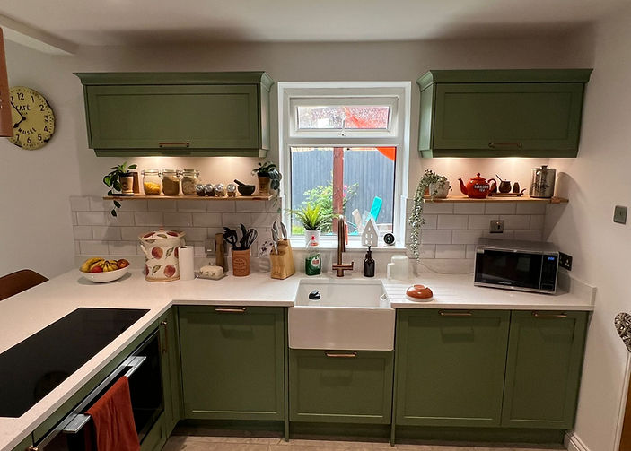 Sage green kitchen cabinets, open shelving, and farmhouse sink