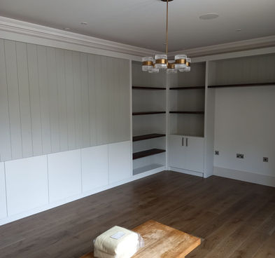 A spacious modern living room featuring white cabinets, a wooden coffee table, and minimalistic decor.