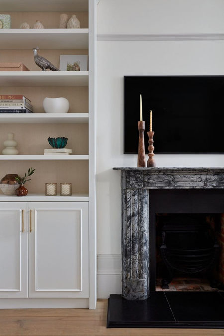 Living room with a marble fireplace, built-in shelves, and decorative items.