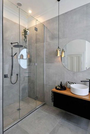 Sleek bathroom with a glass-enclosed shower, round mirror, and minimalist vanity.