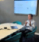 Besprechungsraum. Ein Mann sitzt vor dem Bildschirm und hält einen Vortrag.