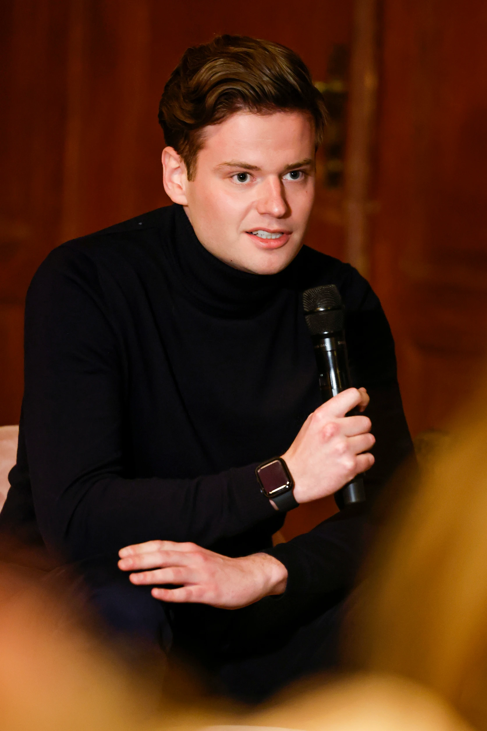 Ein Mann spricht auf einem Panel in ein Mikrofon und beteiligt sich an der Diskussion.