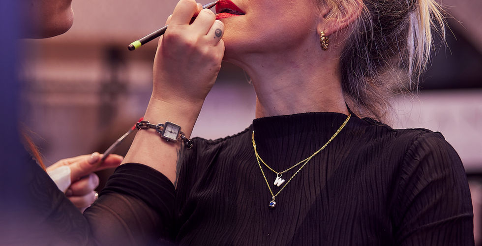 Eine Visagistin trägt Lippenstift auf – ein intimer Moment kurz vor dem großen Auftritt, voller Fokus, Ruhe und Vorfreude.