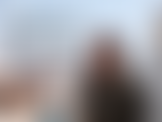 Porträt einer Frau in einem zerstörten Gebiet; im Hintergrund provisorische Unterkünfte und Menschen. Daneben steht ein eindringliches Zitat über die Situation von Frauen und Kindern in Gaza von Kriegsreporterin Sophia Maier.