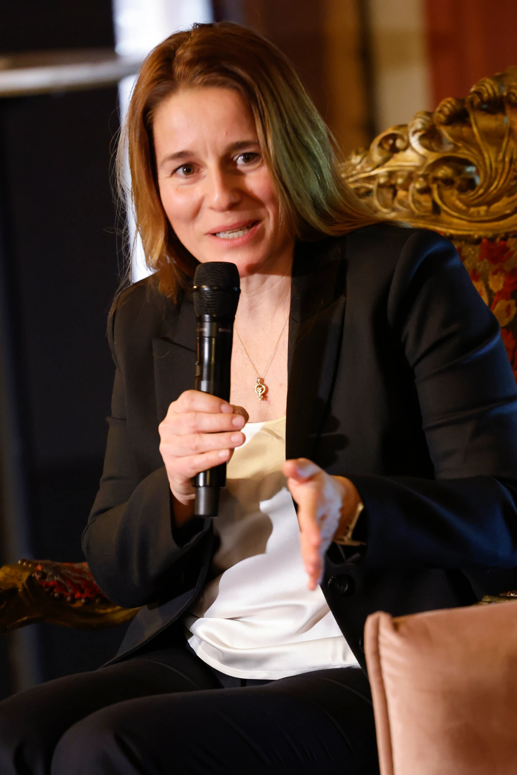 Eine Frau spricht auf einem Panel in ein Mikrofon und gestikuliert während ihres Beitrags.