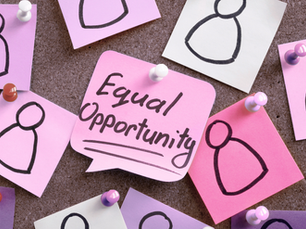 Mehrere rosa und weiße Notizzettel mit einfachen Personen-Skizzen sind an einer Pinnwand befestigt; in der Mitte steht „Equal Opportunity“.
