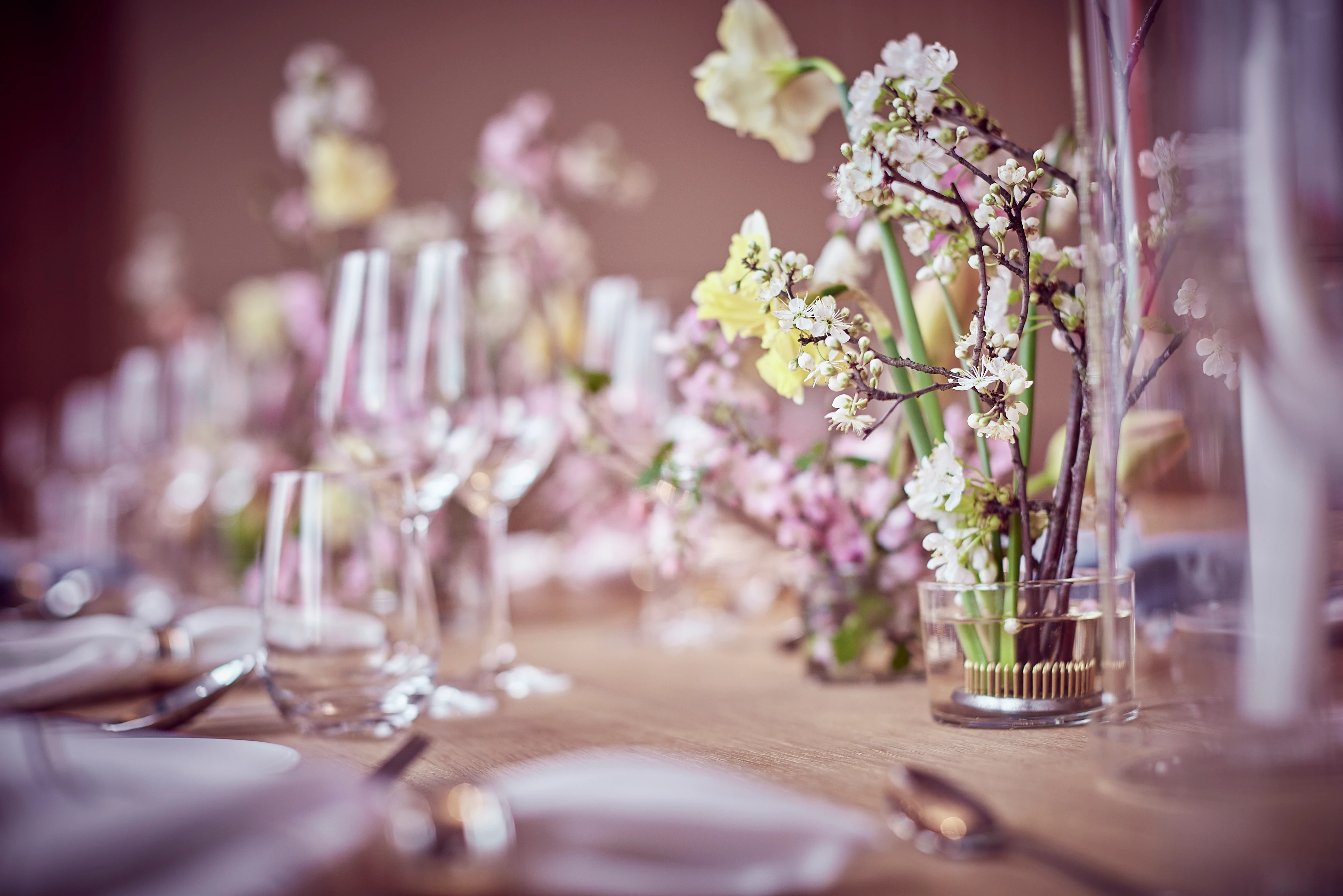 Auf einem gedeckten Tisch stehen mehrere Gläser und kleine Vasen mit Blumen, die für eine dekorative Atmosphäre sorgen.