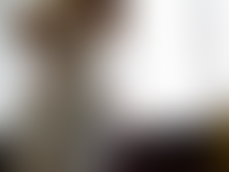 Schwangere Frau steht am Fenster, hält sich den unteren Rücken und wirkt angespannt, mögliches Zeichen für Rückenschmerzen während der Schwangerschaft.