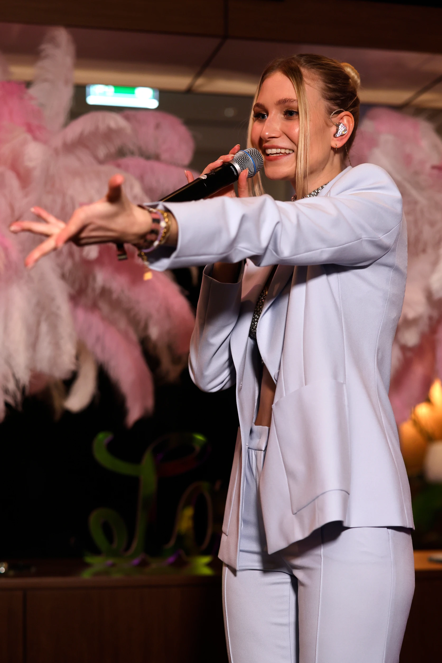 Sängerin im hellen Anzug performt und streckt die Hand ins Publikum.