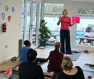 An image for Jo Taylor from Mulberry Wellness - Hosting a corporate wellness talk in front of an audience sitting on yoga mats