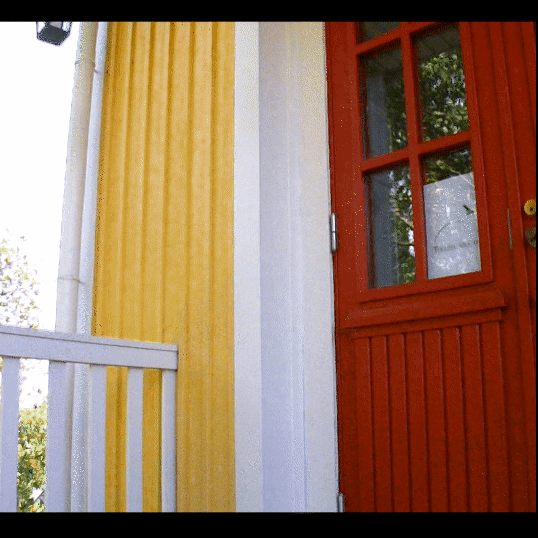 Moving image of an old farmhouse door, whit a sign for tuulihaukka oy on it's window. A lamp is moving on the wind