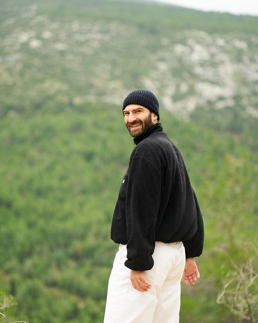 Thumbnail: Irregular Movement of Arts: Andi Xhuma wearing the I.M.A Fleece, in black, which features an embroidery design on the back.