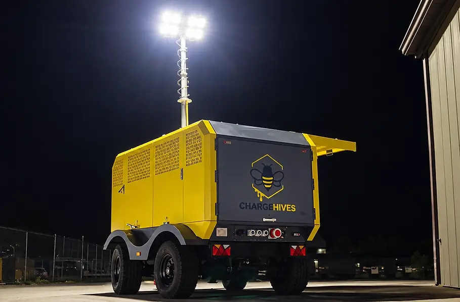ChargeHives mobile battery energy storage system at night with its light tower on and bright