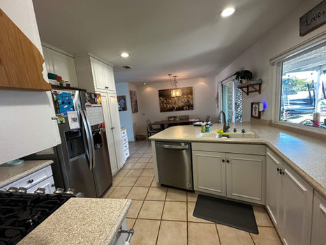 Before photo showing the L-shaped layout of the original San Marcos kitchen with tile floors and upper cabinets.