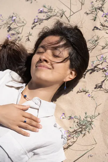 Close-up of a model wearing a Red Cocci accessory in the windy Tarifa dunes.