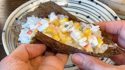 A image of temaki sushi with crab salad toppings.