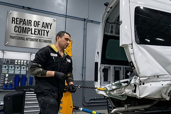 Auto body technician sanding car body for repair