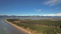 Nelson's Rabbit Island Beach: serene waves, blue skies, majestic Tasman hill range, and charming towns of Richmond and Stoke.