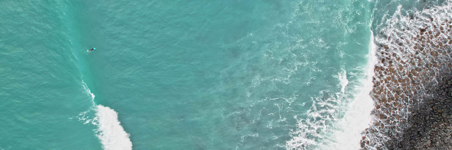 Panoramic bird's-eye view of a surfer catching a wave at Magnet Bay. Landscape photography, gallery. 