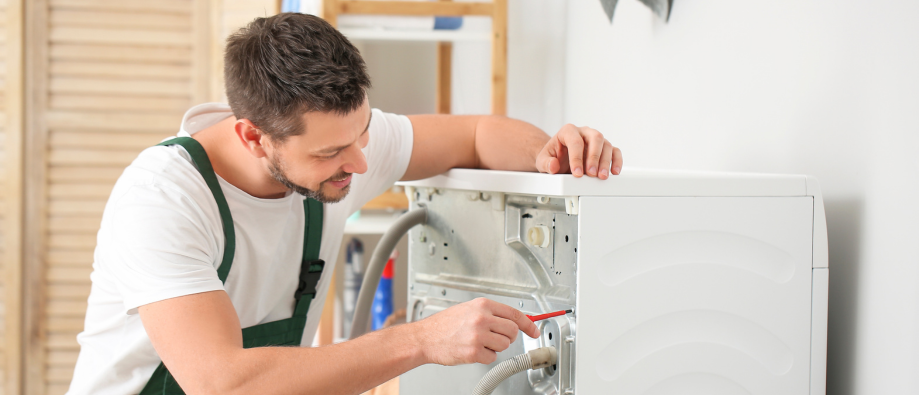 Worker Repairing Washing Machine Indoors