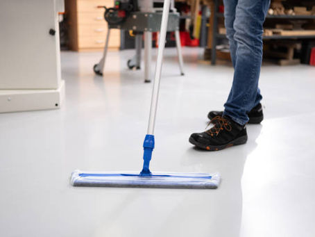 Person mopping a clean floor in a workshop.