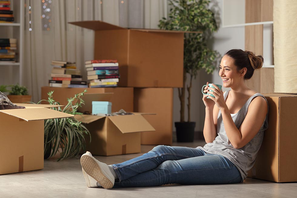 Millennial woman sitting on the floor of newly purchased home.