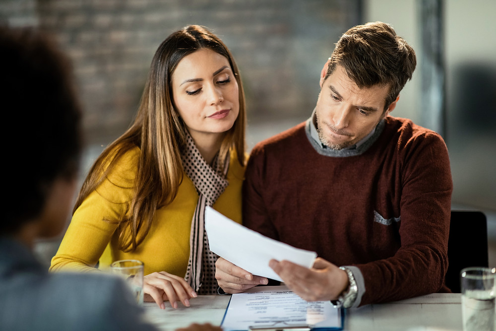 Young couple looks over their current coverage with their insurance agent.