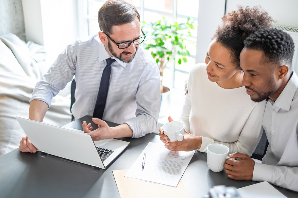 Insurance agent sits with young couple for their annual policy review.