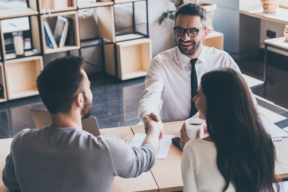 Insurance agent shakes hands with customer after assessing risk and reviewing/updating policies.