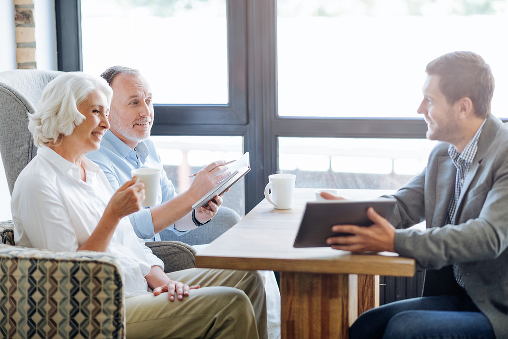Insurance agent sits with elderly couple to review their coverage.