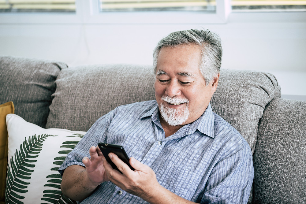 man sitting on couch scrolling on his smart phone
