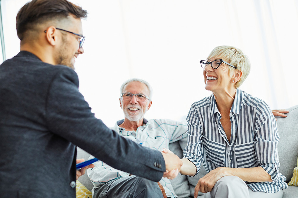 insurance agent sits with elderly couple for a customer insurance review meeting.