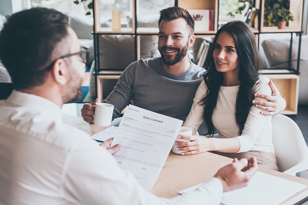 Insurance agent meeting with young couple to review their policies and increase retention.