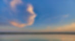 Calm lake under a dramatic sunset sky.