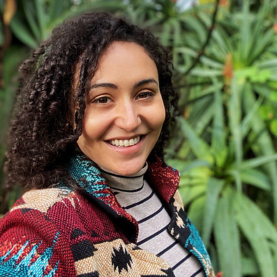 Caitlin's greeting image, smiling in the botanical garden.