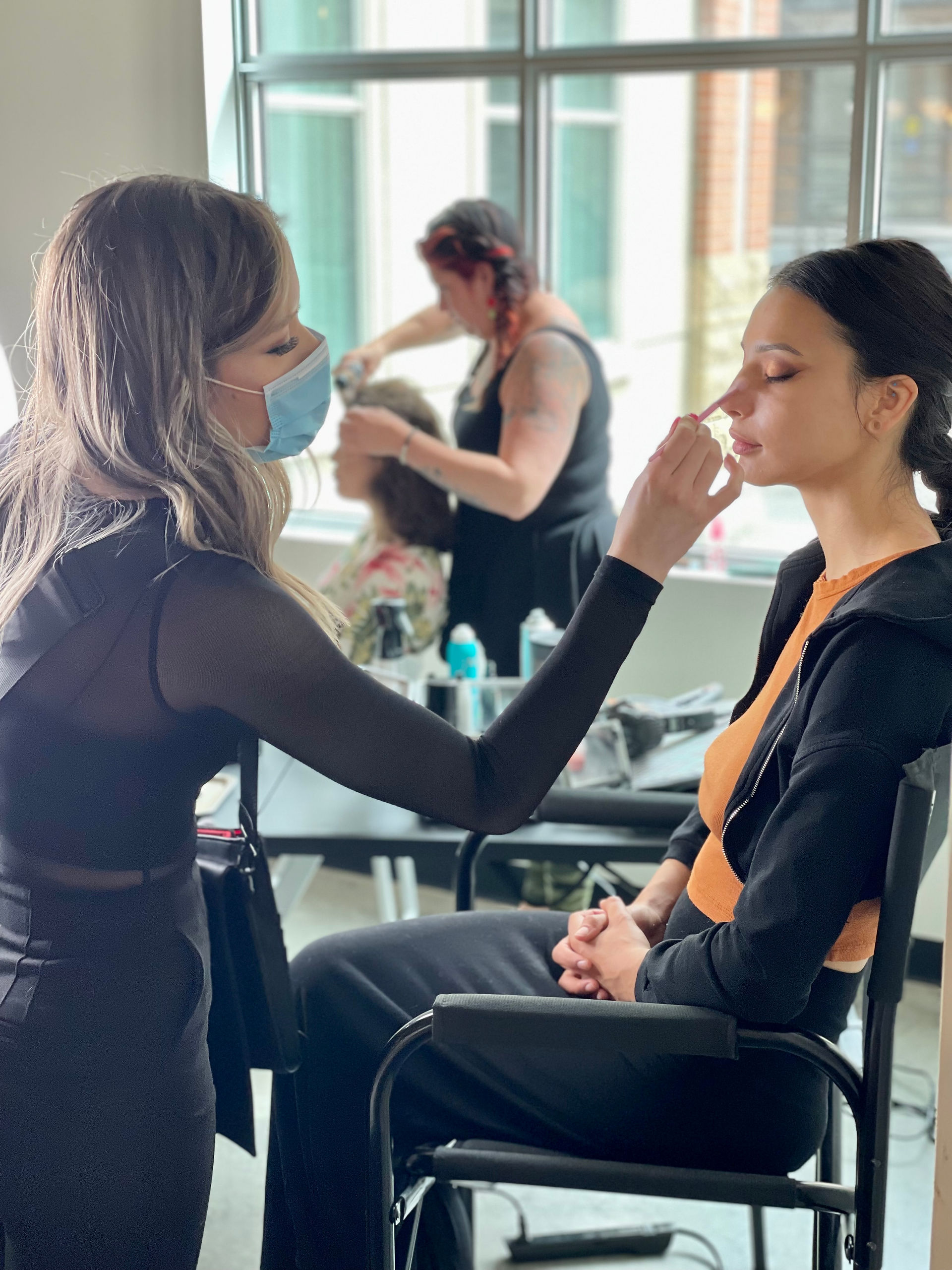 Makeup artist applying foundation to model in a beauty workshop setting.