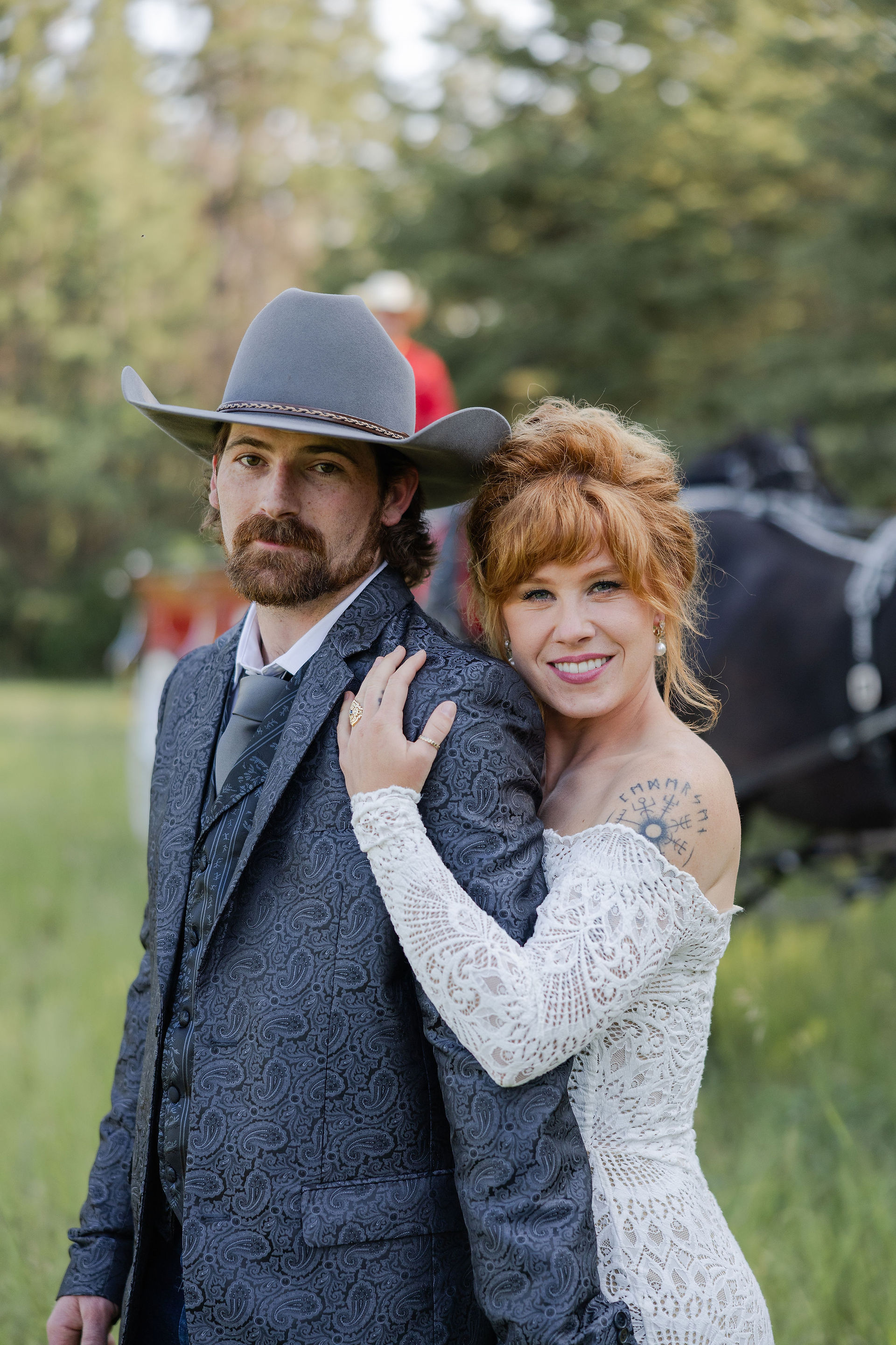 Man in cowboy hat and suit, woman in white lace dress, embracing.