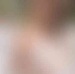 Smiling woman in off-shoulder gown and pearls holding a teacup.