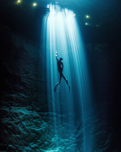 Freediver surrounded by natural light inside a Mexican cenote