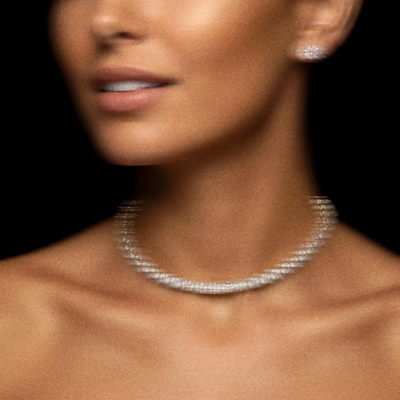 Cropped photo of a woman wearing a diamond necklace and earrings, on black