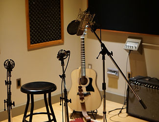 photograph of a recording studio with microphone and guitar