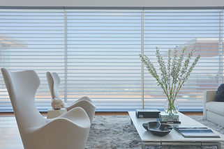 Silhouette sheers and shadings in a living room with two white chairs and a white table.